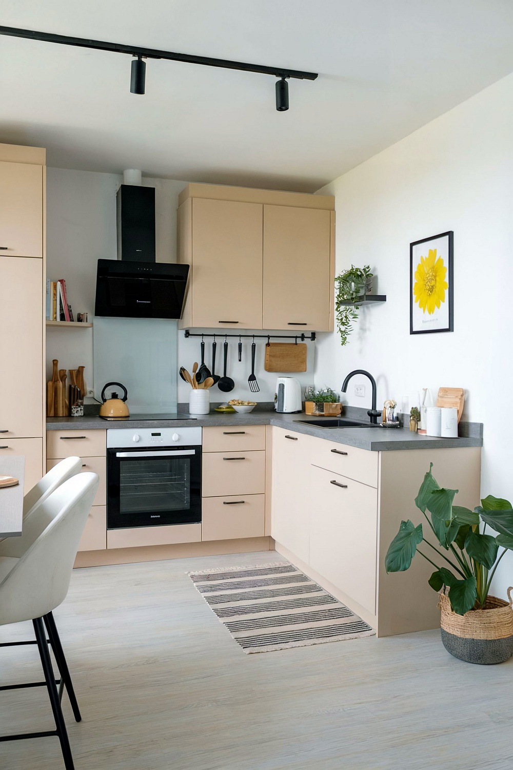 Beige L-Küche mit dezentem Dekor, schwarzer Dunstabzugshaube und Pflanzen-Details