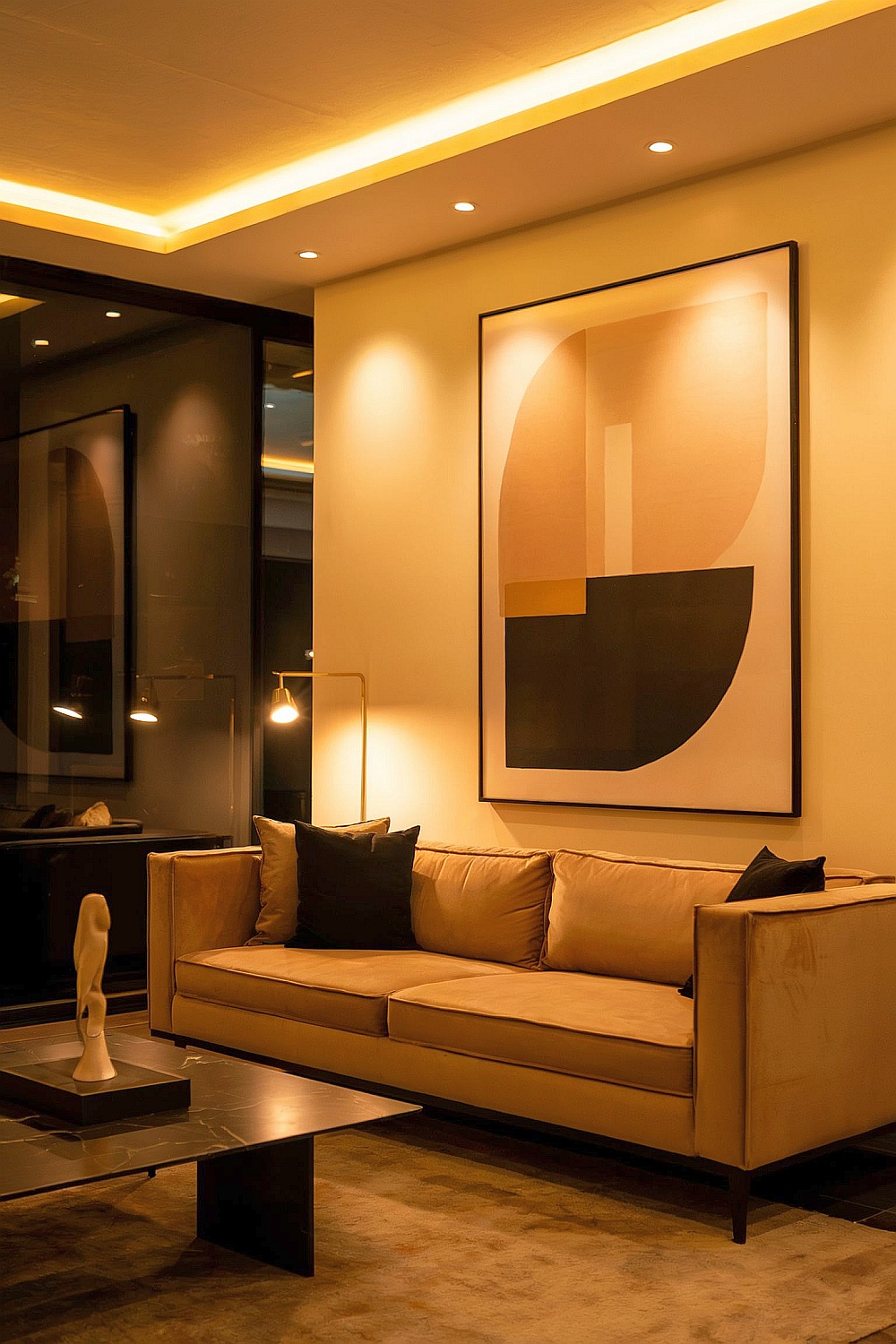 Modernes Wohnzimmer in Beige-Gold-Schwarz mit Sofa, indirekter Beleuchtung und abstraktem Wandbild.