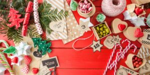 Adventskalender Inhalt: kleine Schachteln, Bonbons und Zahlenanhänger auf einem roten Holztisch