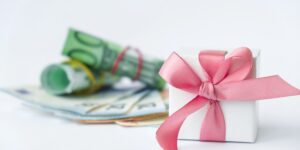 Geld verpacken zur Hochzeit: gerollte Euroscheine und ein weißes Geschenk mit rosa Satinschleife