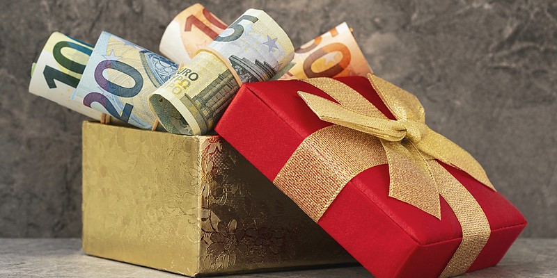 Geldgeschenke zum Geburtstag: gerollte Euroscheine in einer goldenen Geschenkbox mit roter Schleife