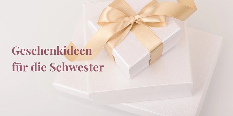 Geschenkideen für die Schwester: zwei weiße Geschenkboxen mit goldenem Satinband auf hellem Hintergrund