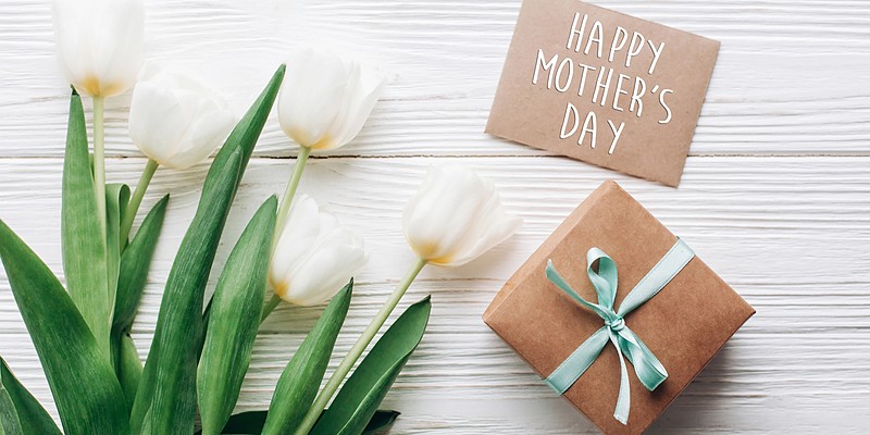 Muttertag-Geschenke: weiße Tulpen, eine Karte mit Happy Mother's Day und ein Geschenk mit türkisem Band